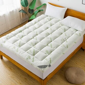 Bamboo mattress topper on a wooden bed with pillows.