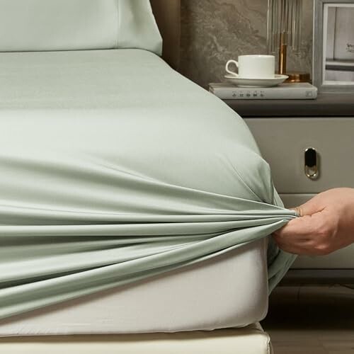 Person fitting a bed sheet on a mattress.