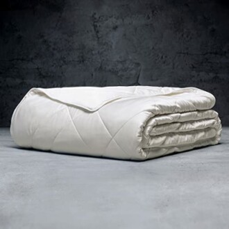 Folded white comforter on a gray floor