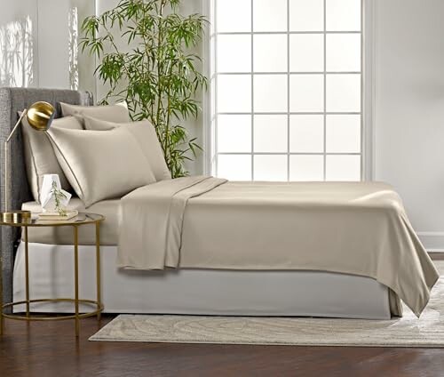 Modern bedroom with a neatly made bed, side table, and indoor plant, showcasing the beauty of the Queen Sheets by Pure Bamboo.