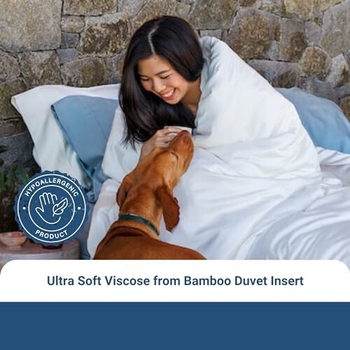 Woman wrapped in a white duvet with a dog, hypoallergenic product label visible.